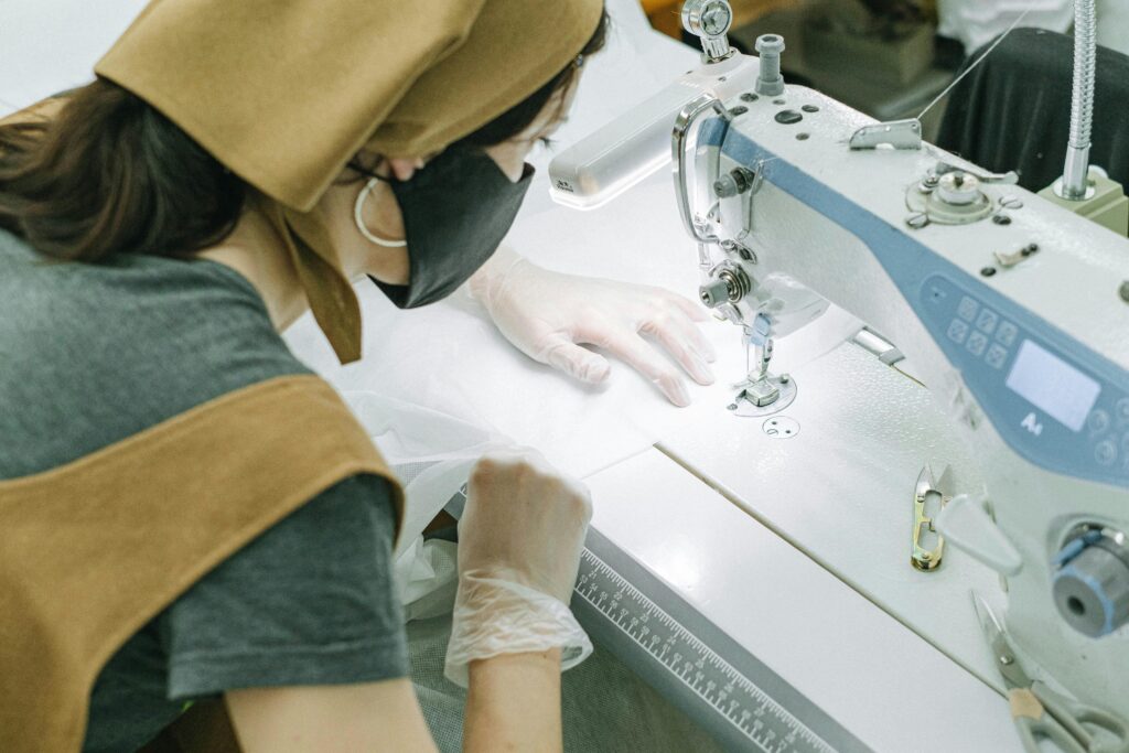 A woman working with a sewing machine in a workshop environment, creating textile products.