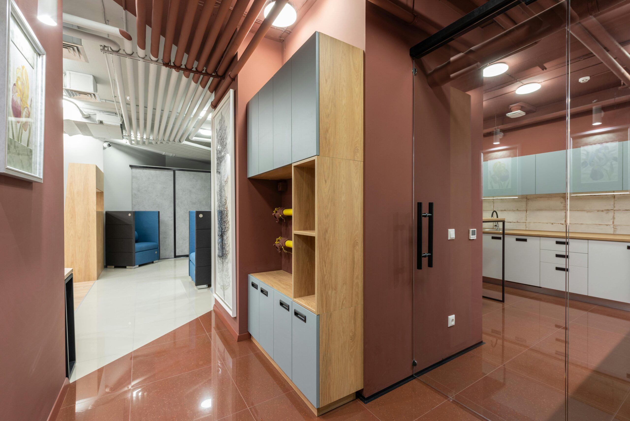 Corner of cabinet separating spacious workplace with new furniture and modern kitchen with counters and tiled floor