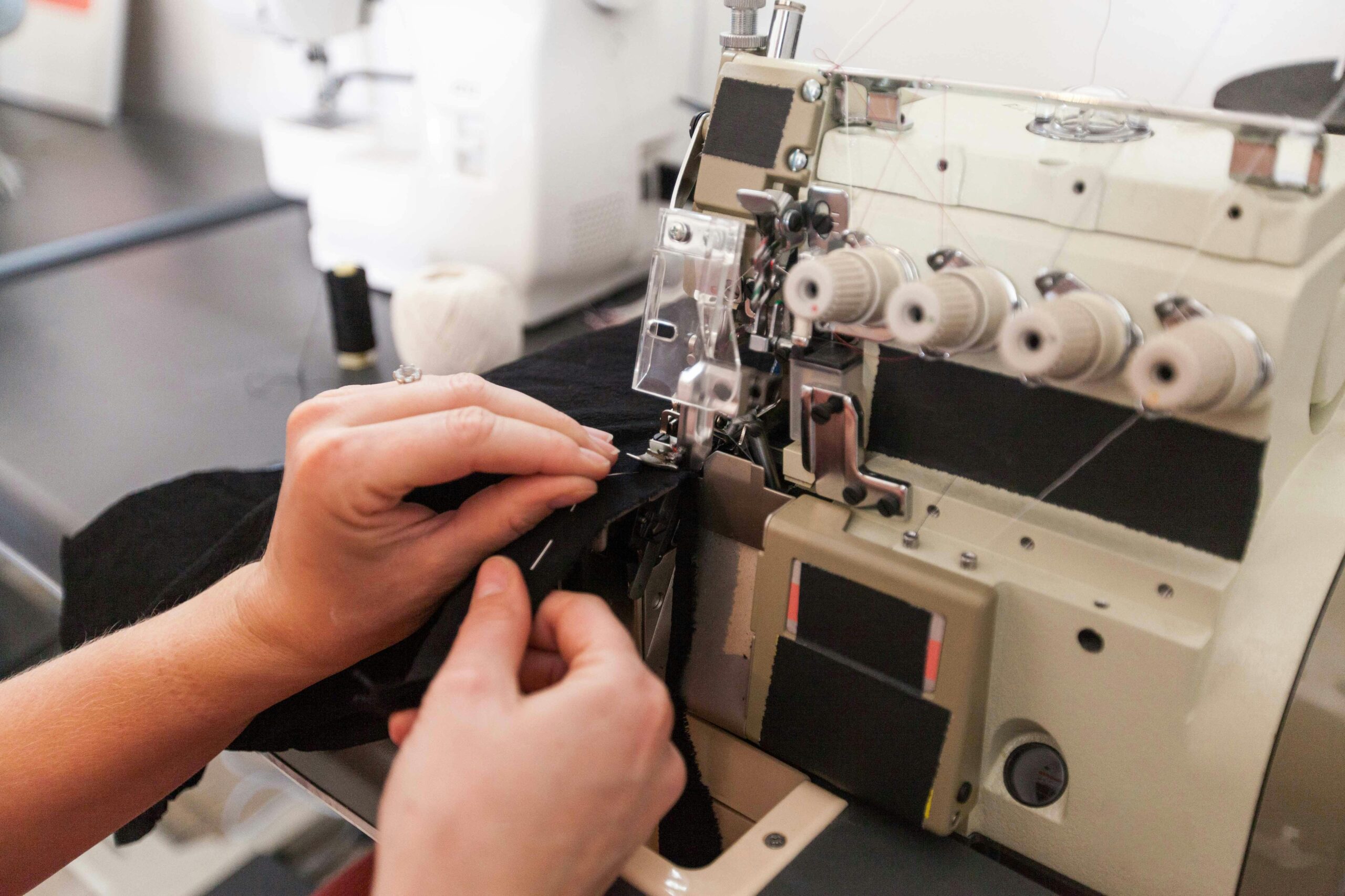 Detailed view of hands operating an overlock machine in a sewing studio.